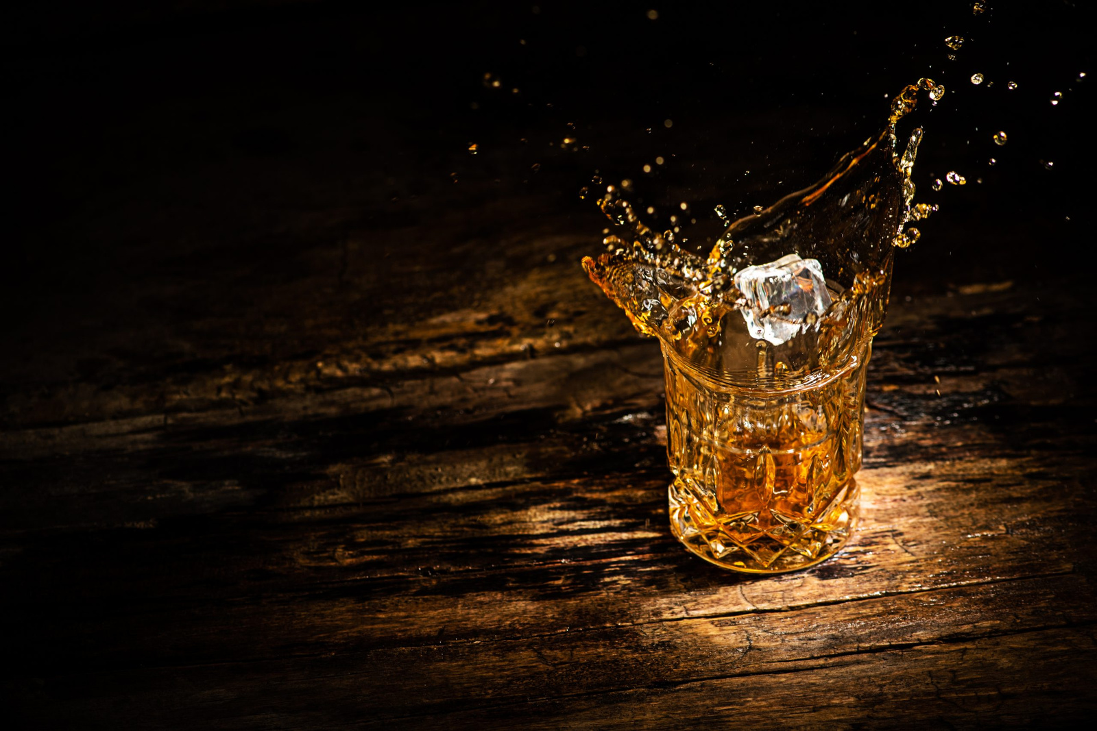 A glass of whiskey with splashes from the ice cube. glass with a